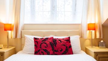 Une chambre d’hôtel avec un lit, deux lampes de chevet, une fenêtre avec des rideaux et une table de chevet sur laquelle se trouve une boîte de mouchoirs.