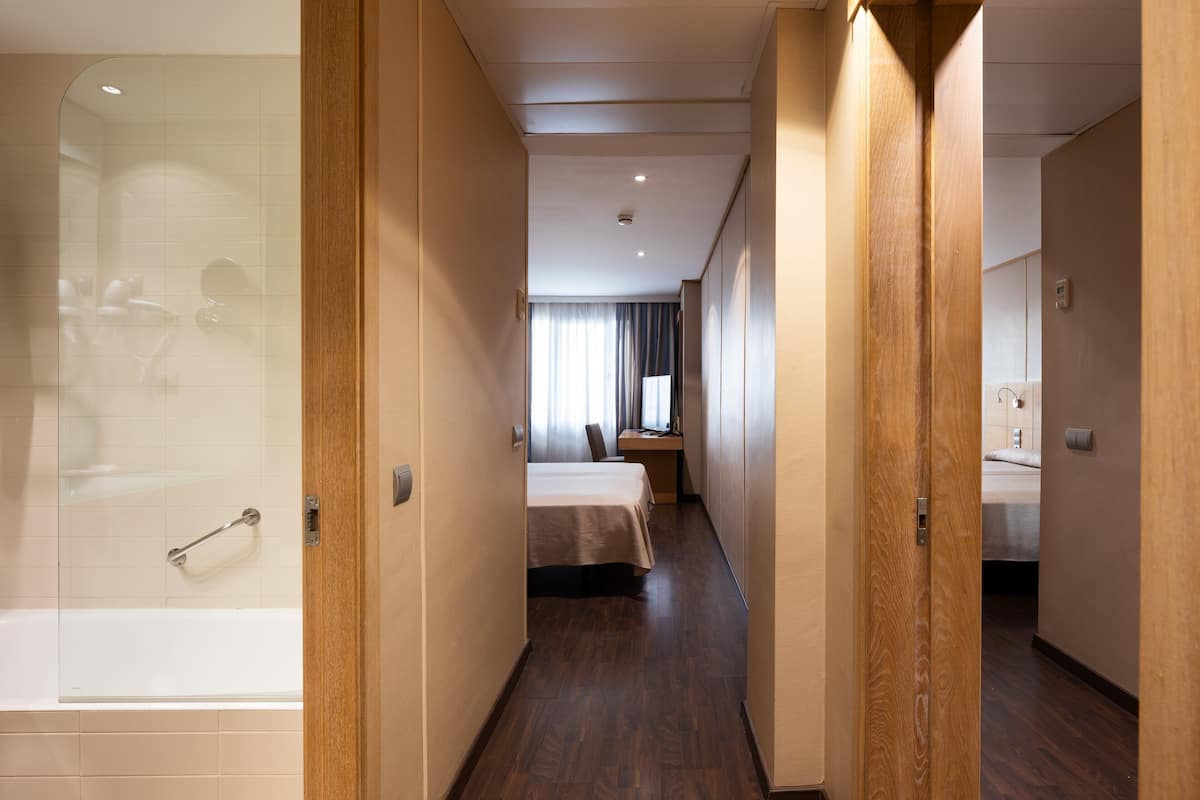 Ein Hotelzimmer mit Dusche, Bett und Schreibtisch.