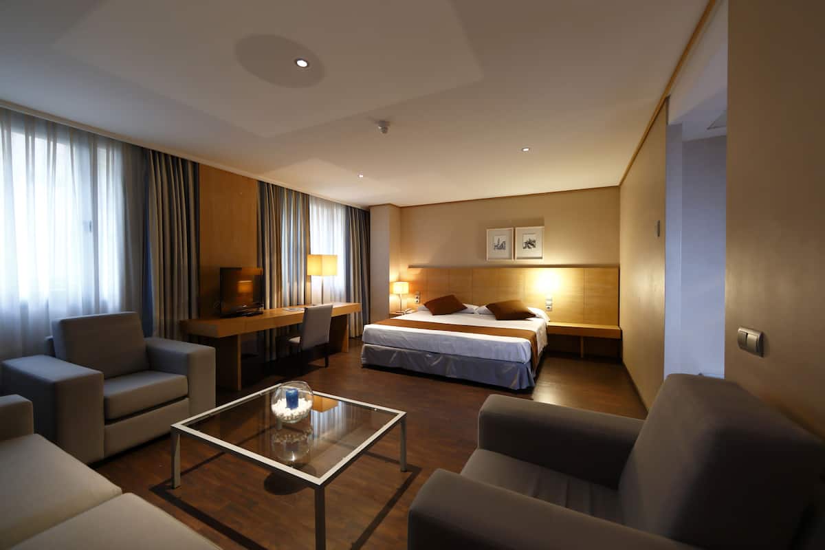 Ein modernes Hotelzimmer mit Bett, Schreibtisch, Sofa und Couchtisch.