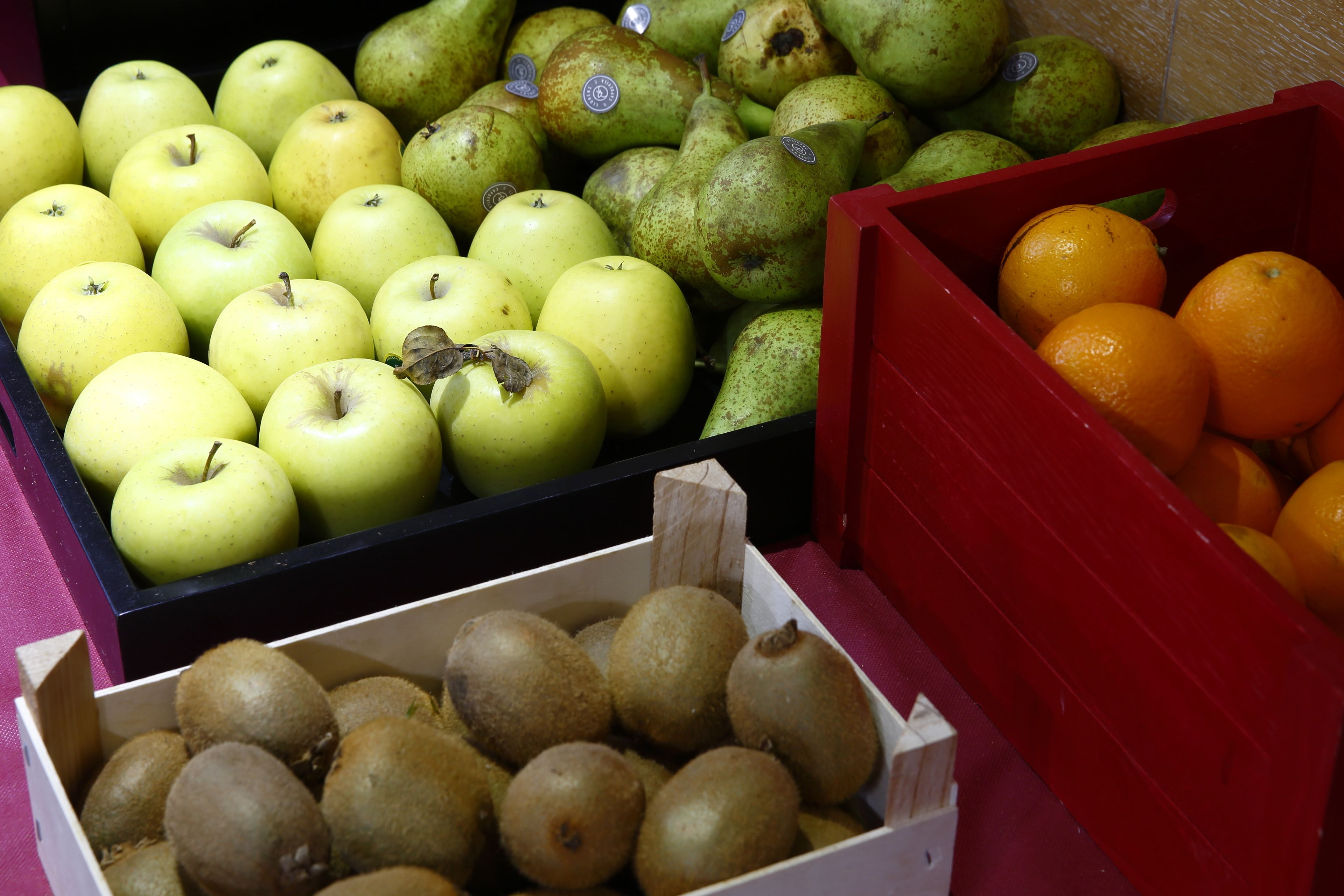 Una exhibición de diversas frutas, como manzanas, peras y naranjas, en cajas individuales.