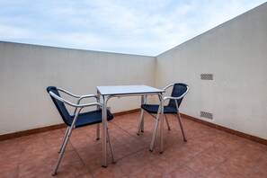 Une petite terrasse extérieure avec une table en métal et deux chaises.