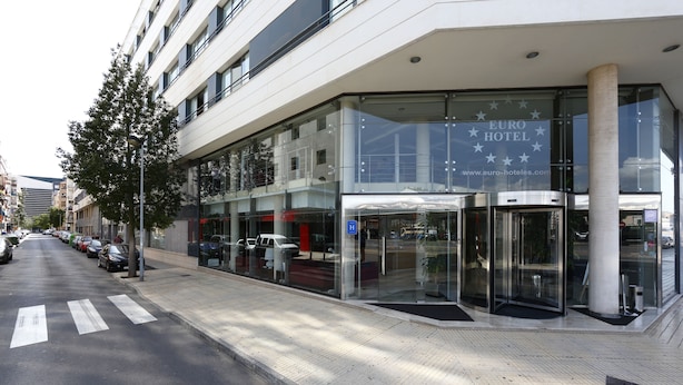 Moderni hotellin sisäänkäynti, jossa on lasijulkisivu, pyörivä ovi ja selvästi näkyvä Euro Hotel -kyltti.