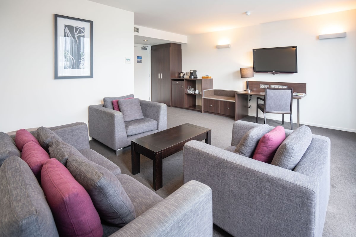 A modern living room with grey sofas, a coffee table, and a flat-screen TV.