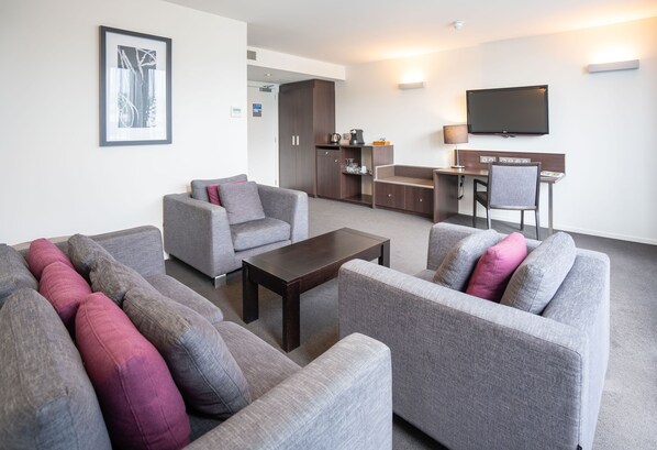 A modern living room with grey sofas, a coffee table, and a flat-screen TV. - Scenic Hotel Dunedin City (Dunedin)