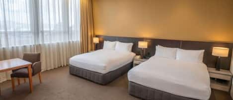 Une chambre d’hôtel avec deux lits, un bureau et une chaise.
