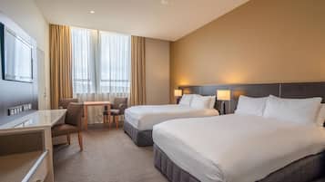 Een hotelkamer met twee bedden, een bureau, een stoel en een klein tafeltje.