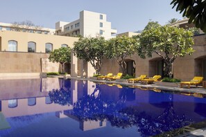 A swimming pool with reflections, sun loungers, and a building with a modern design.