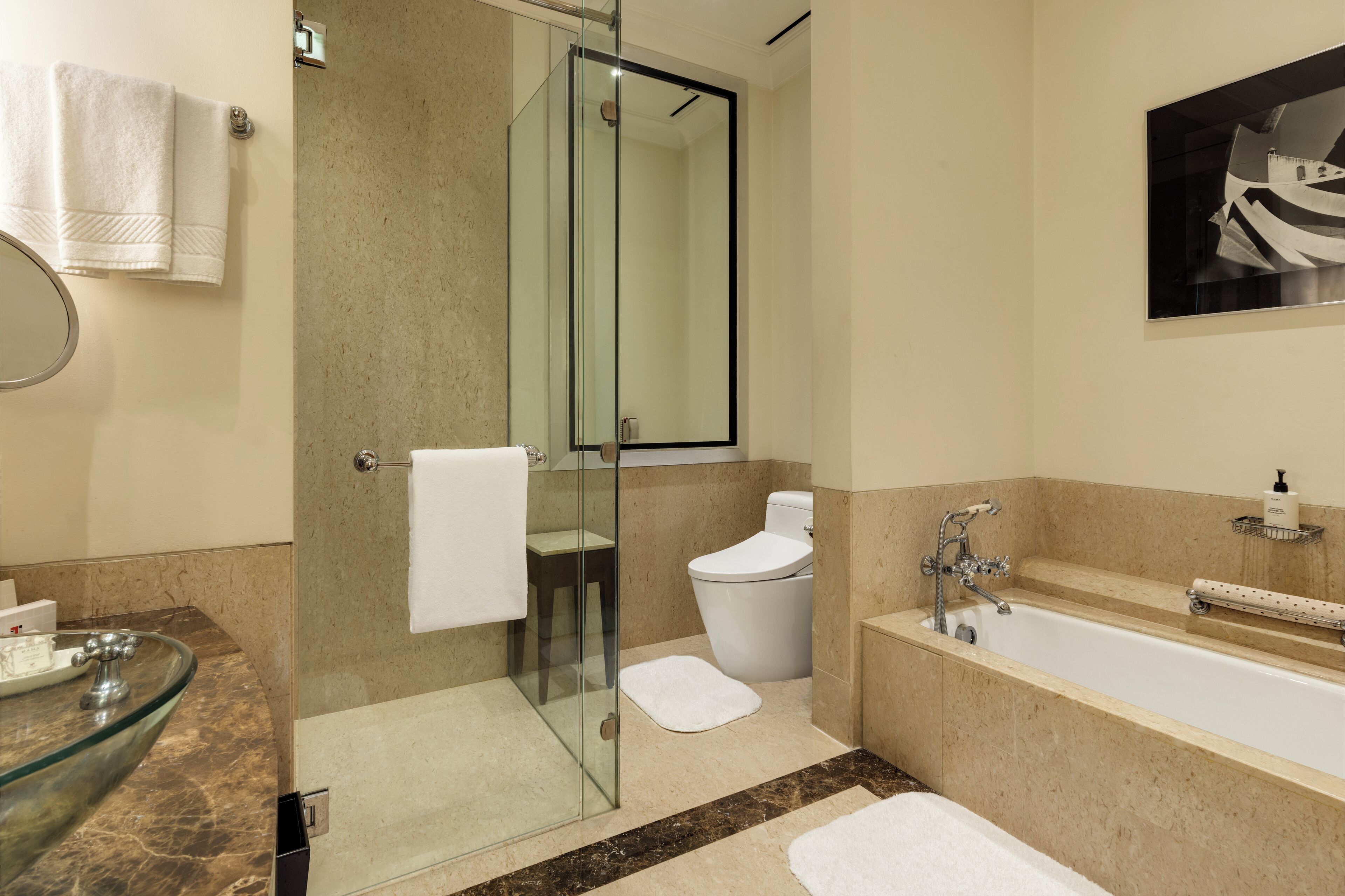 Un baño moderno con ducha de vidrio, una bañera independiente y encimera de mármol.