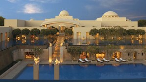 A luxurious resort with a large pool, outdoor seating, and a grand entrance.