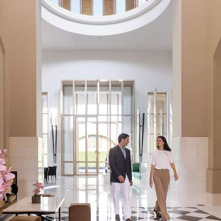 A spacious lobby with a high ceiling, large windows, and a checkered floor.