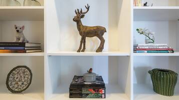 Une bibliothèque agrémentée d’objets décoratifs, notamment une figurine de cerf, une petite figurine de chien, des livres et un vase avec des fleurs.