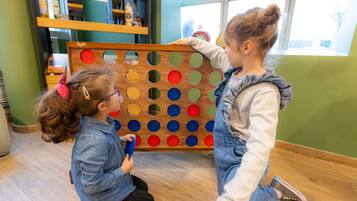 Dos niños jugando un juego de mesa en el interior, con una ventana al fondo.