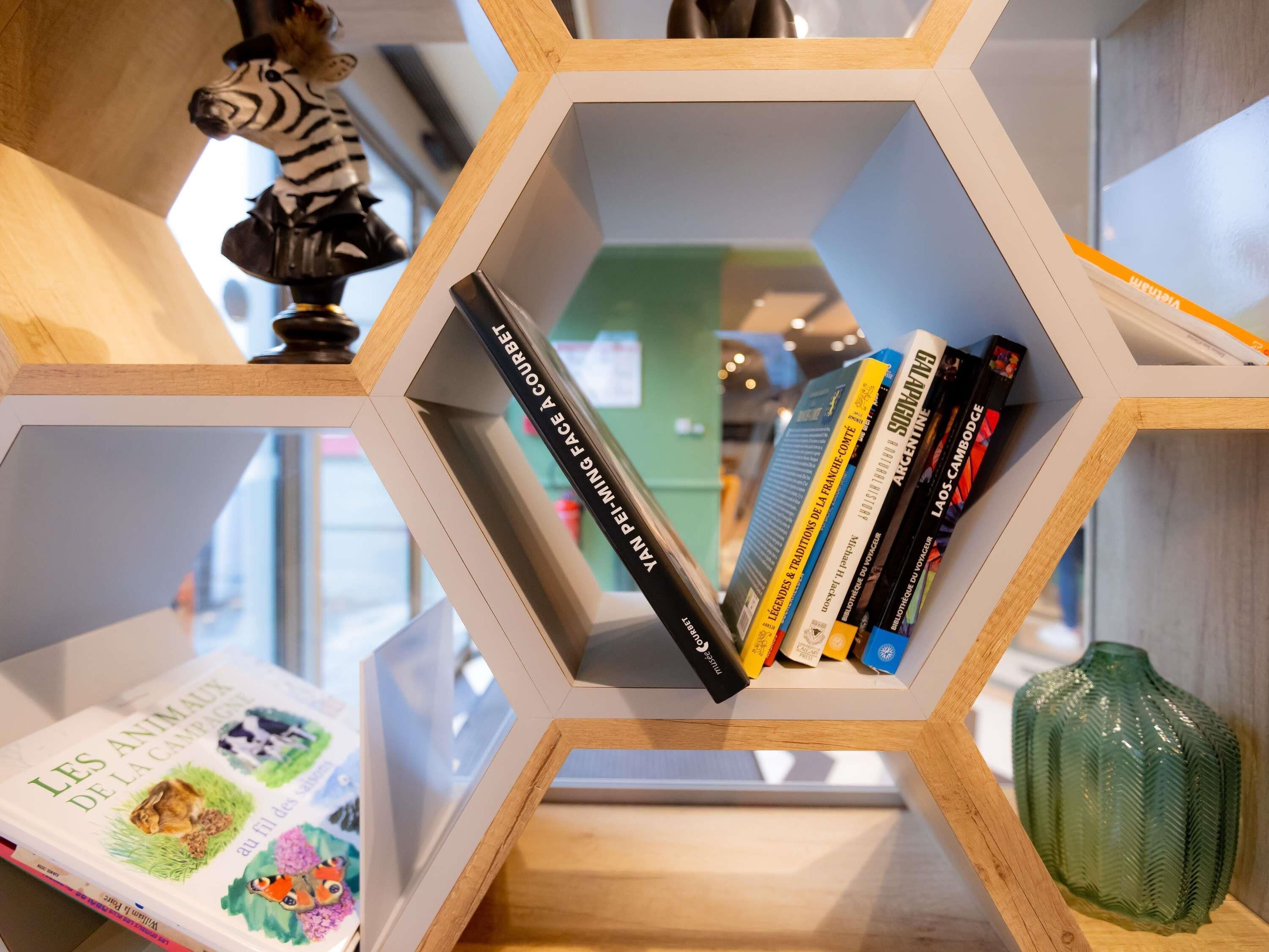 Una estantería hexagonal con libros y un objeto decorativo.