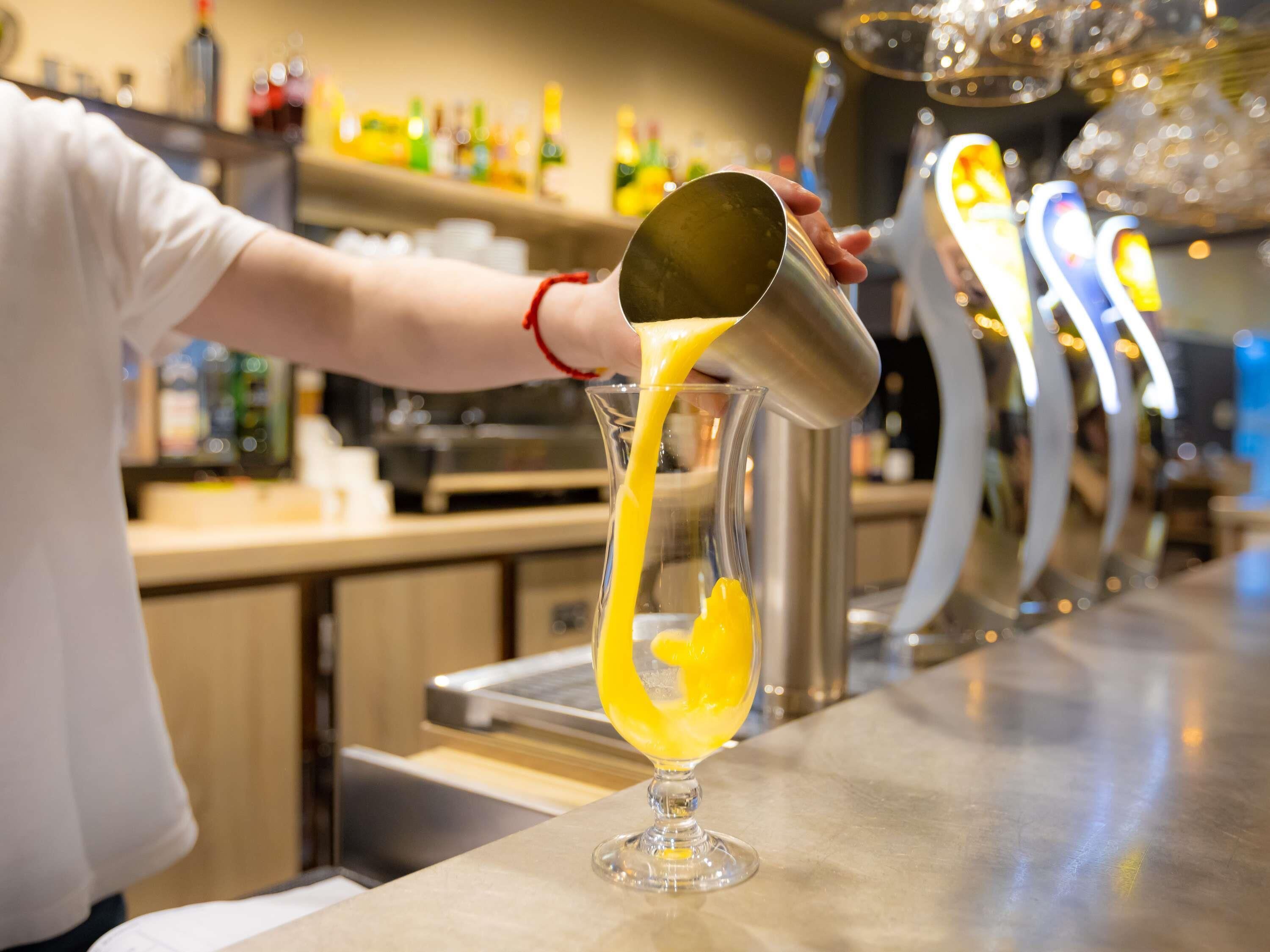 Ein Barkeeper gießt eine gelbe Flüssigkeit in ein Glas ein.