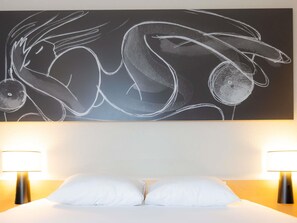 A hotel room with a large abstract artwork on the wall, two bedside lamps, and a double bed with white bedding. - ibis Besançon Centre La City (Besancon)