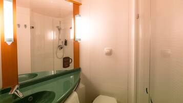 A bathroom with a green sink, a white toilet, and a glass-enclosed shower.