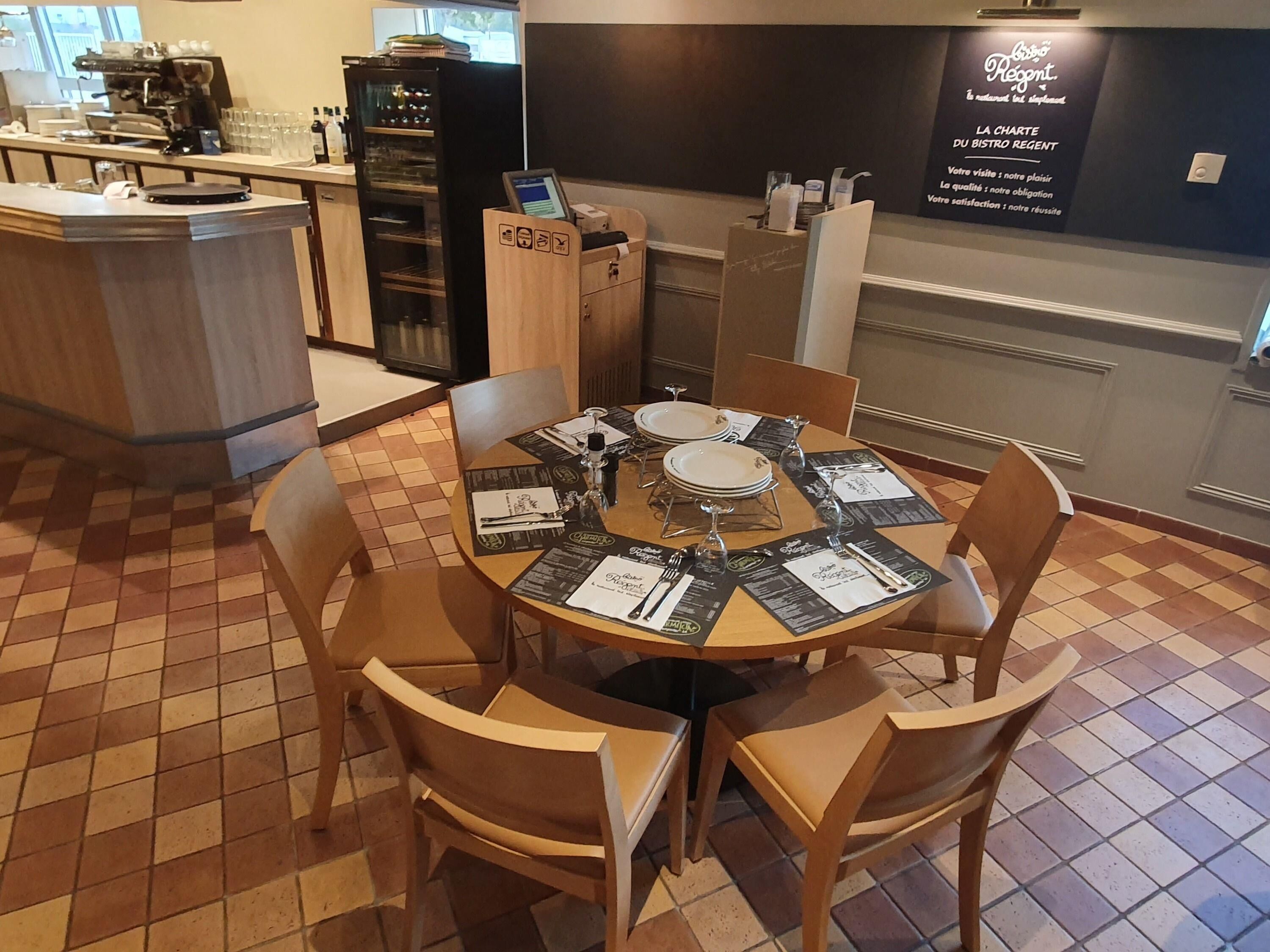 Een restauranttafel voor vier personen, een koffieapparaat en een menukaartstandaard.