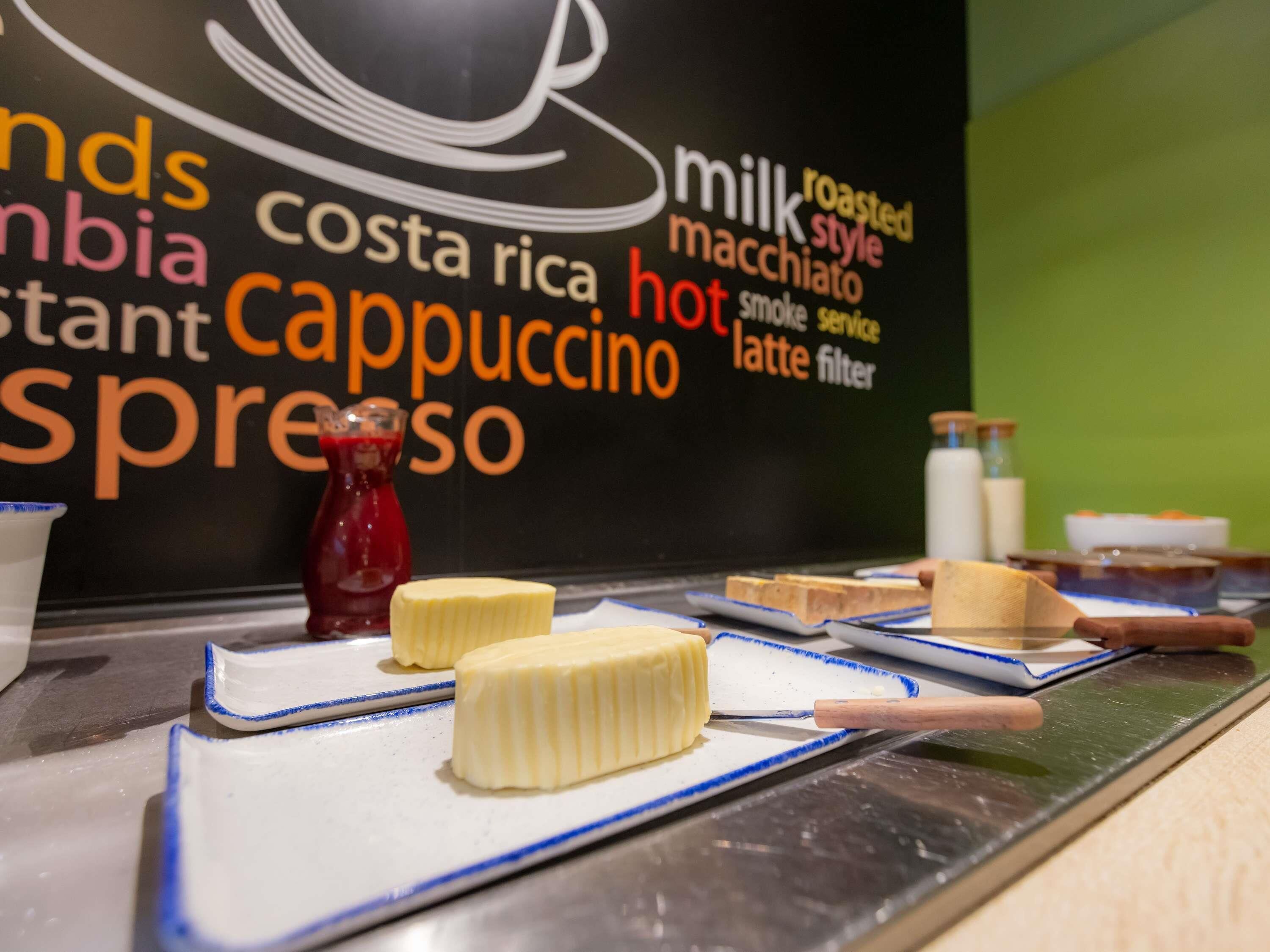 Una cafetería con un cartel que muestra opciones de café y una selección de pasteles en platos.
