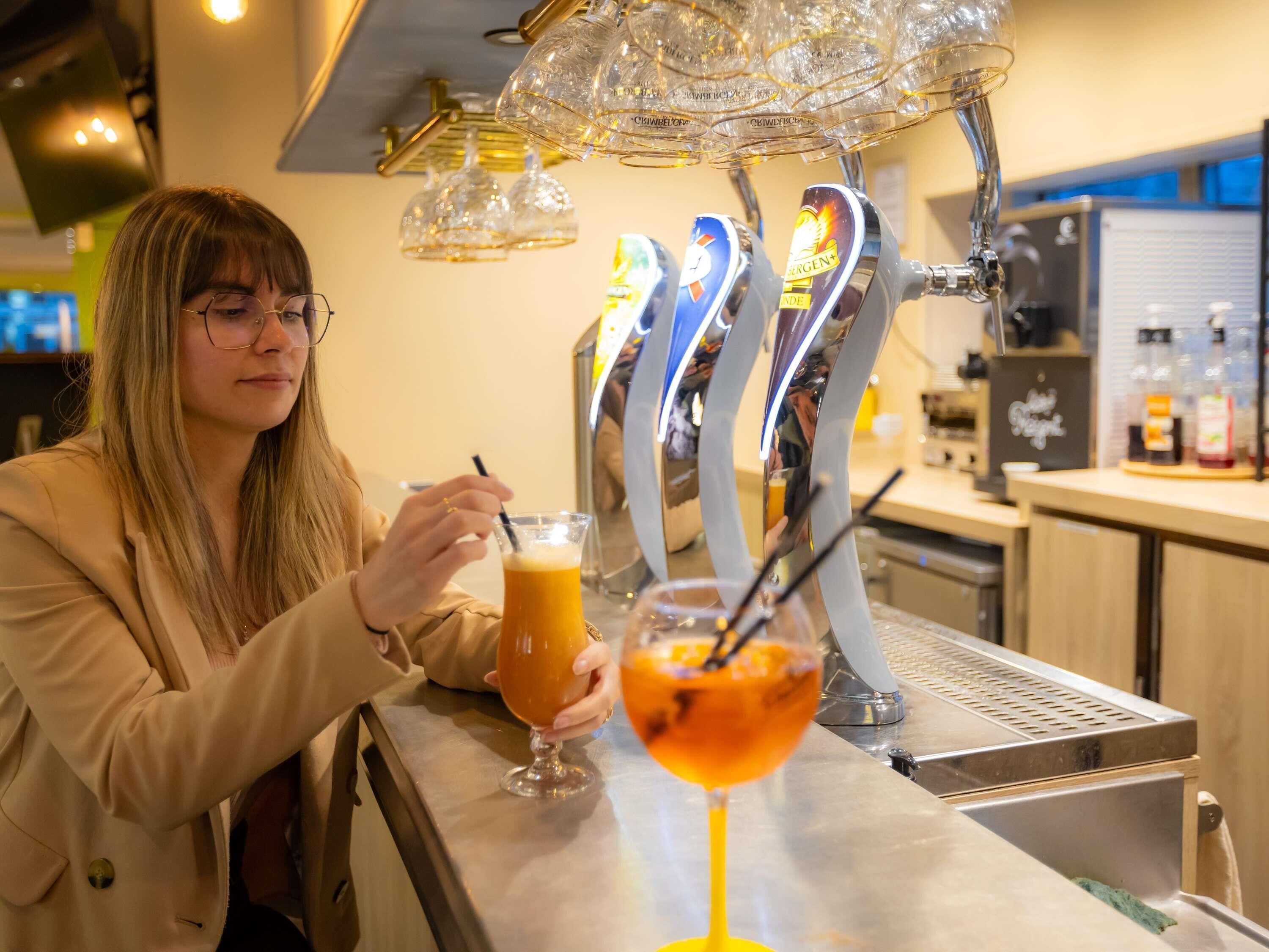 A person at a bar with multiple beer taps and a drink in a glass.