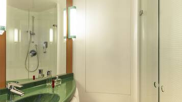 A bathroom with a green sink, a mirror, a shower, and a toilet.