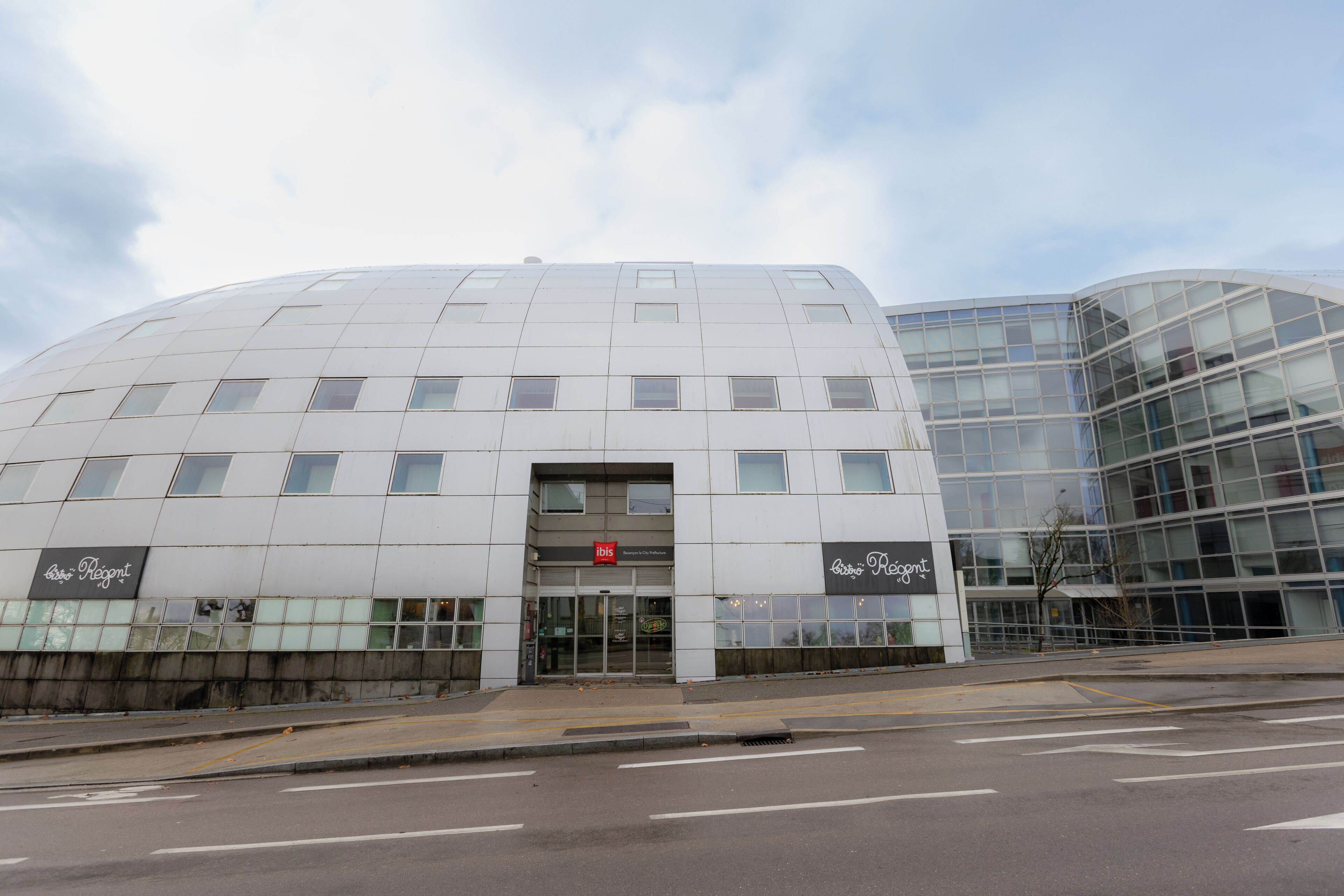 Een modern gebouw met een vlakke gevel en een ruime glazen ingang.