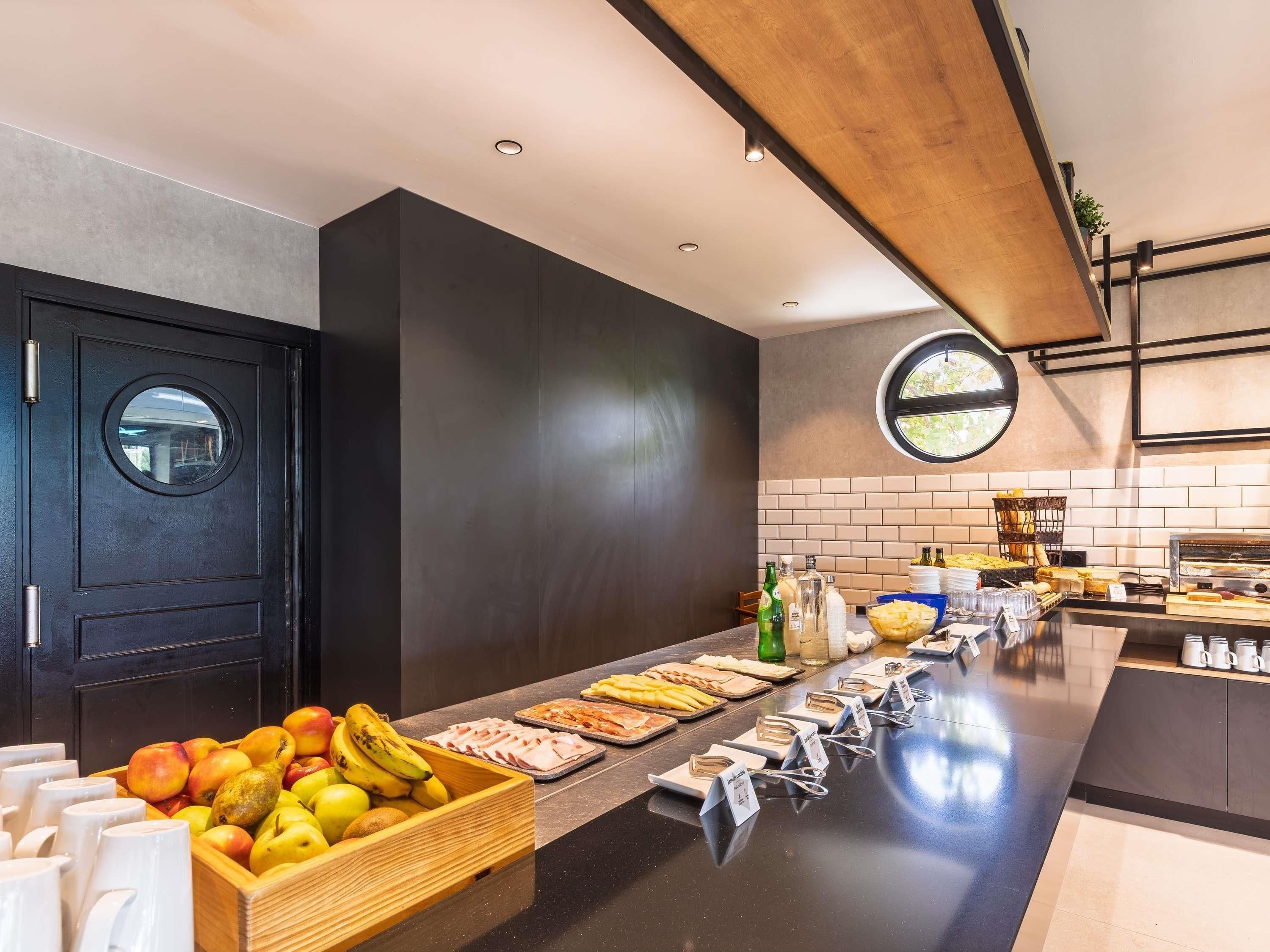 A modern kitchen with a black door, a fruit display, and a buffet counter with various food items.