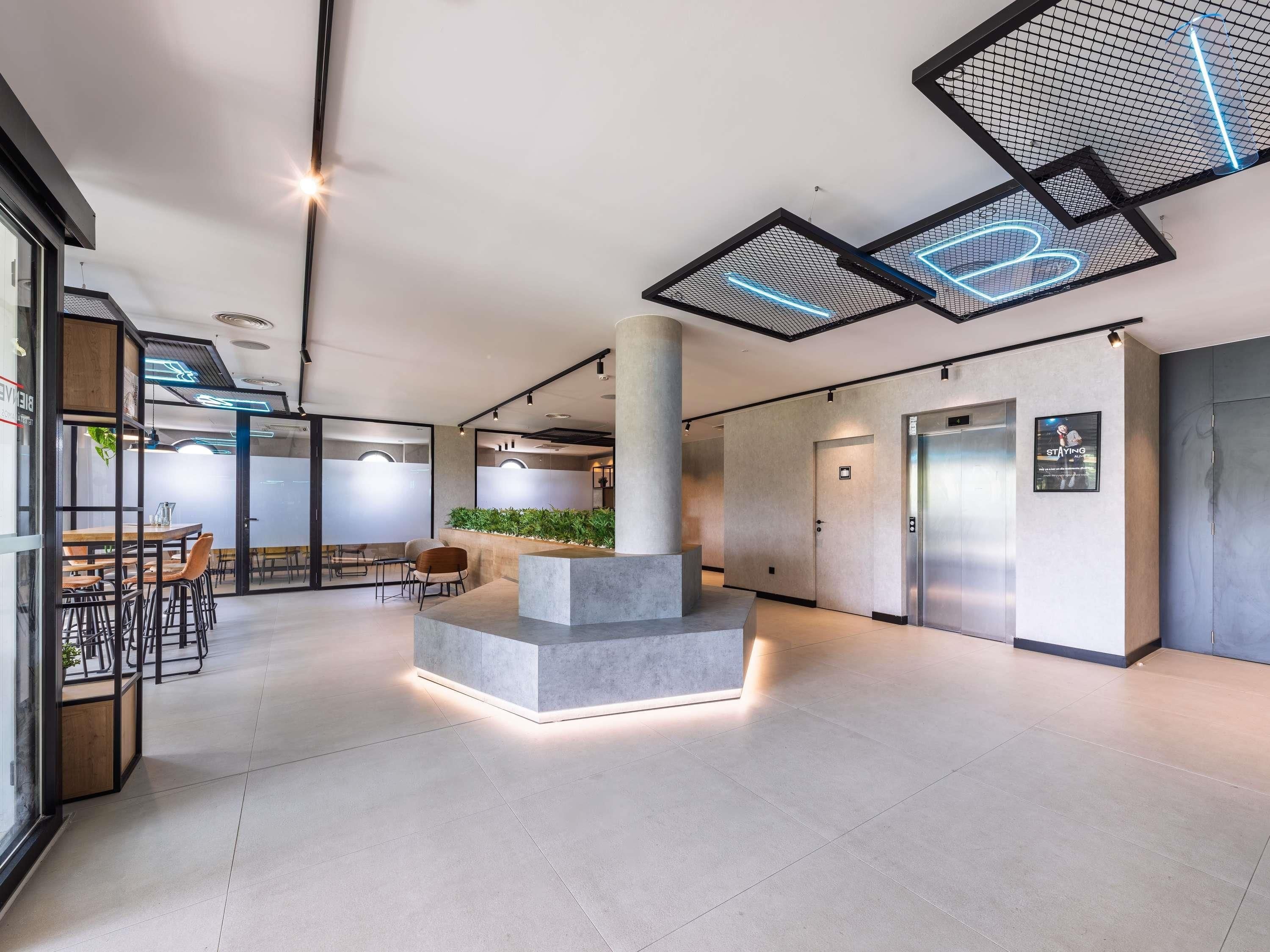 Un interior moderno con una zona de estar central, un mostrador de recepción y una escalera.