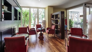 Un interior moderno con sillas rojas, suelo de madera y ventanas amplias.