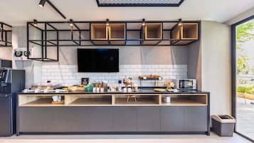Una cocina moderna con televisor de pantalla plana, barra de desayuno y diversos alimentos.