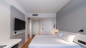 Una habitación de hotel moderna con una cama, un escritorio, un televisor y un papel tapiz estampado.