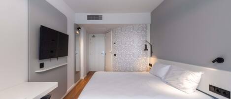 Una habitación de hotel moderna con una cama, un escritorio, un televisor y un papel tapiz estampado.