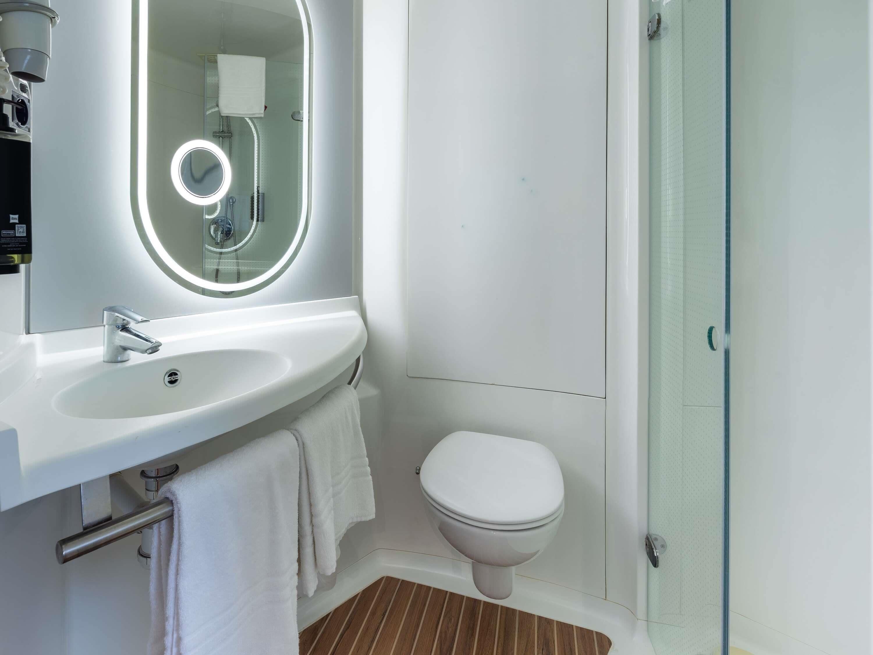 Ein modernes Badezimmer mit Waschbecken, Spiegel und Toilette in Weiß.