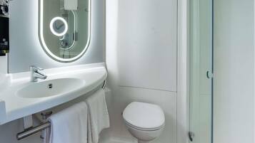 Ein modernes Badezimmer mit Waschbecken, Spiegel und Toilette in Weiß.