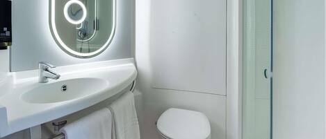 Un baño moderno con un lavamanos, espejo y retrete blancos.