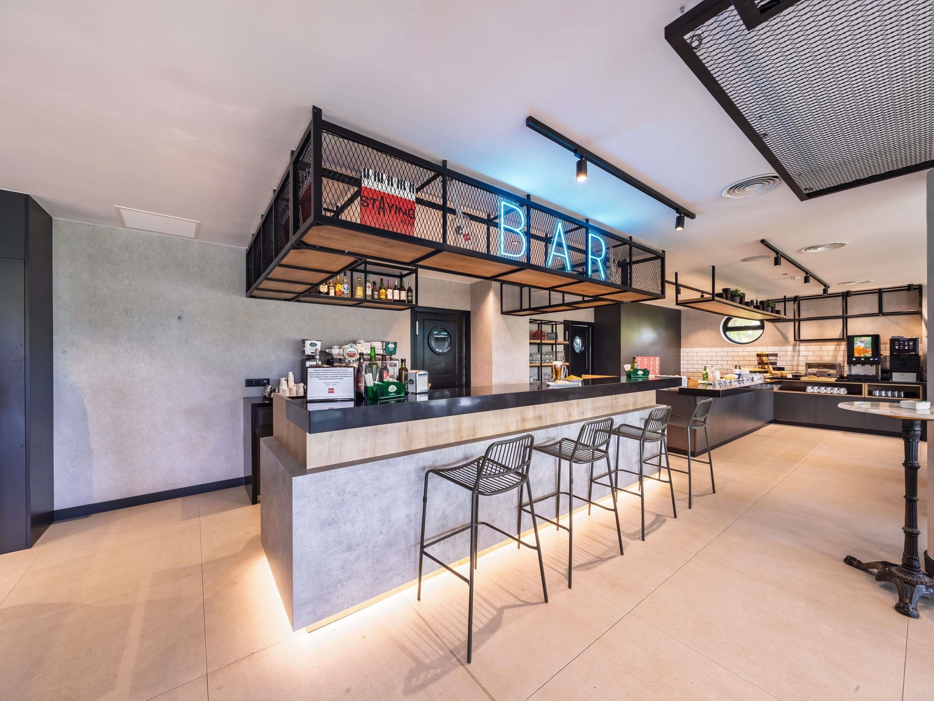 Un'area bar moderna con un bancone, sgabelli e un neon.