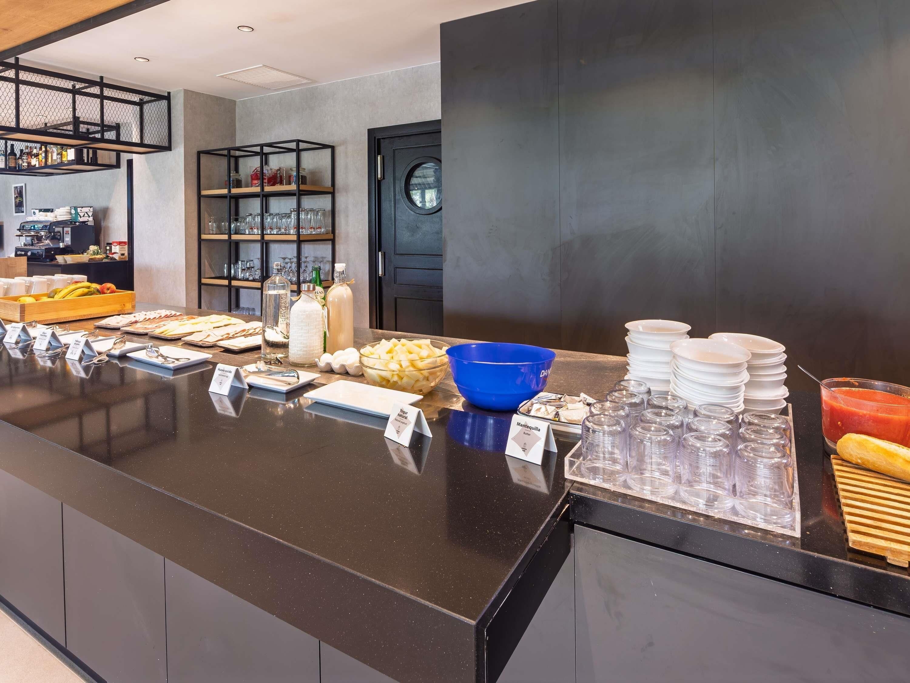 A buffet area with various food items and utensils, including a blue bowl, plates, and condiments.
