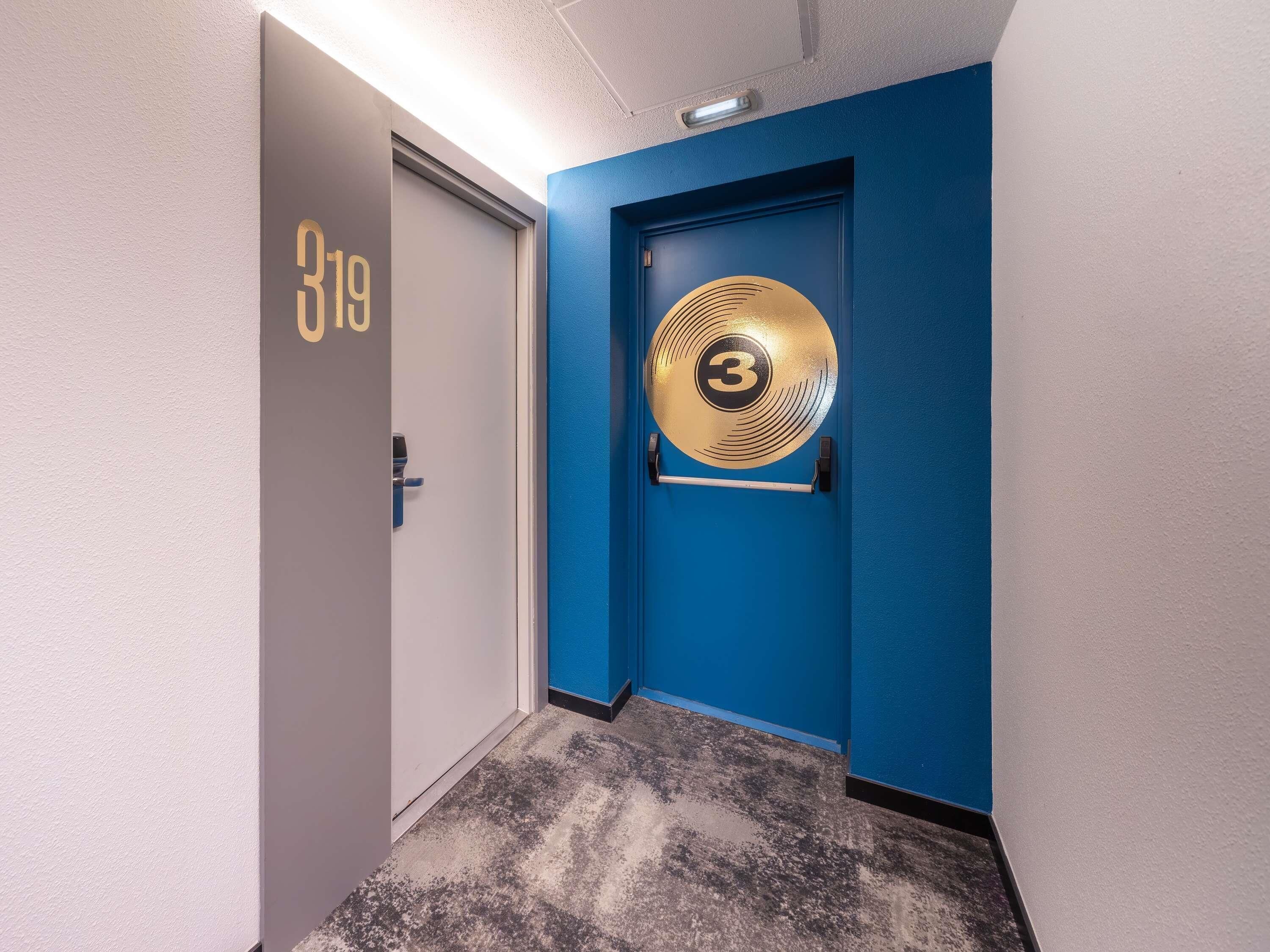 A hallway with a door labeled '319' and a blue door with a circular emblem featuring the number '3'.