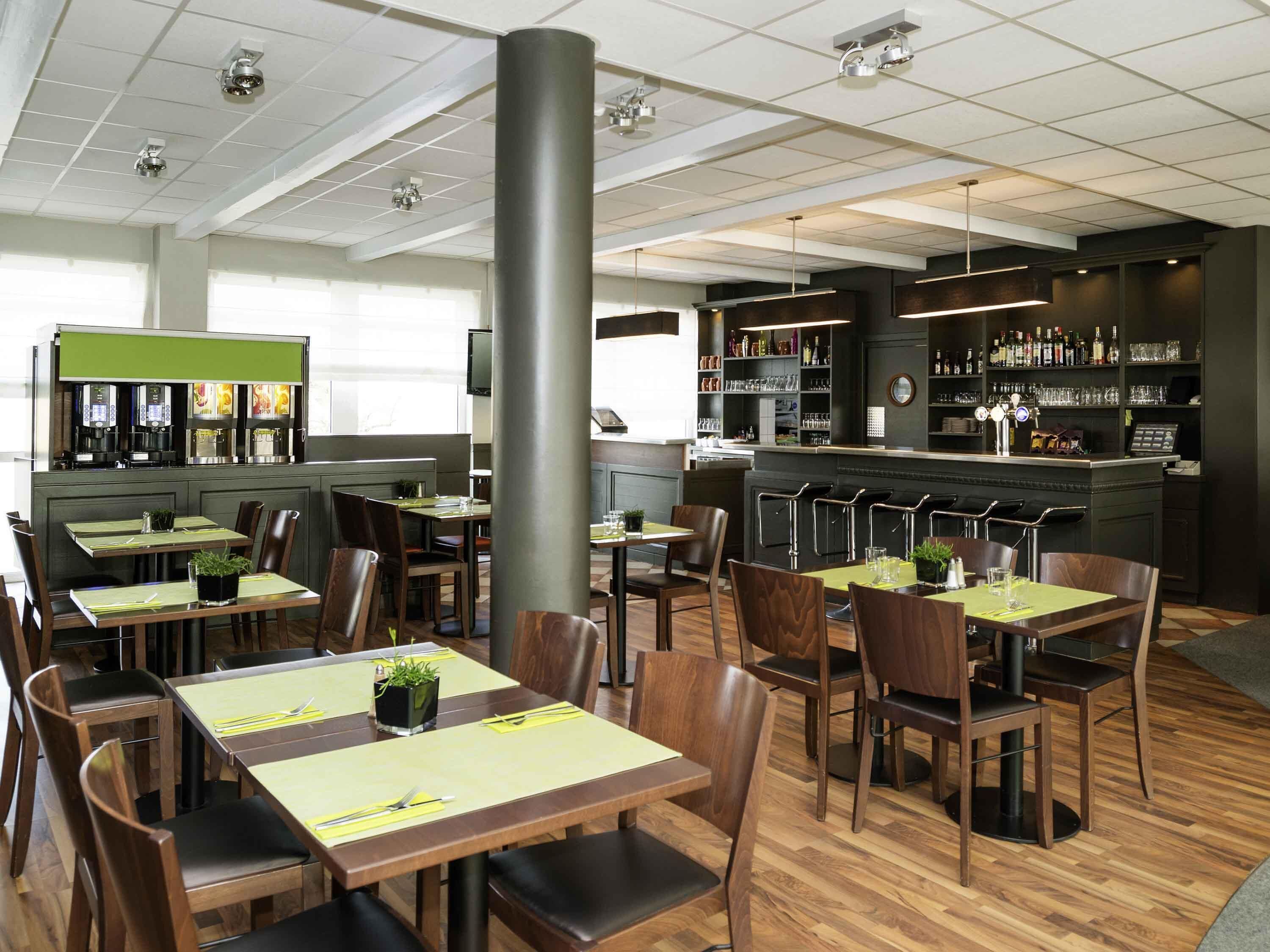 Un restaurant doté de plusieurs tables, de chaises, d’un bar et d’un espace dédié au café.