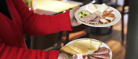 A person holding two plates with various food items.