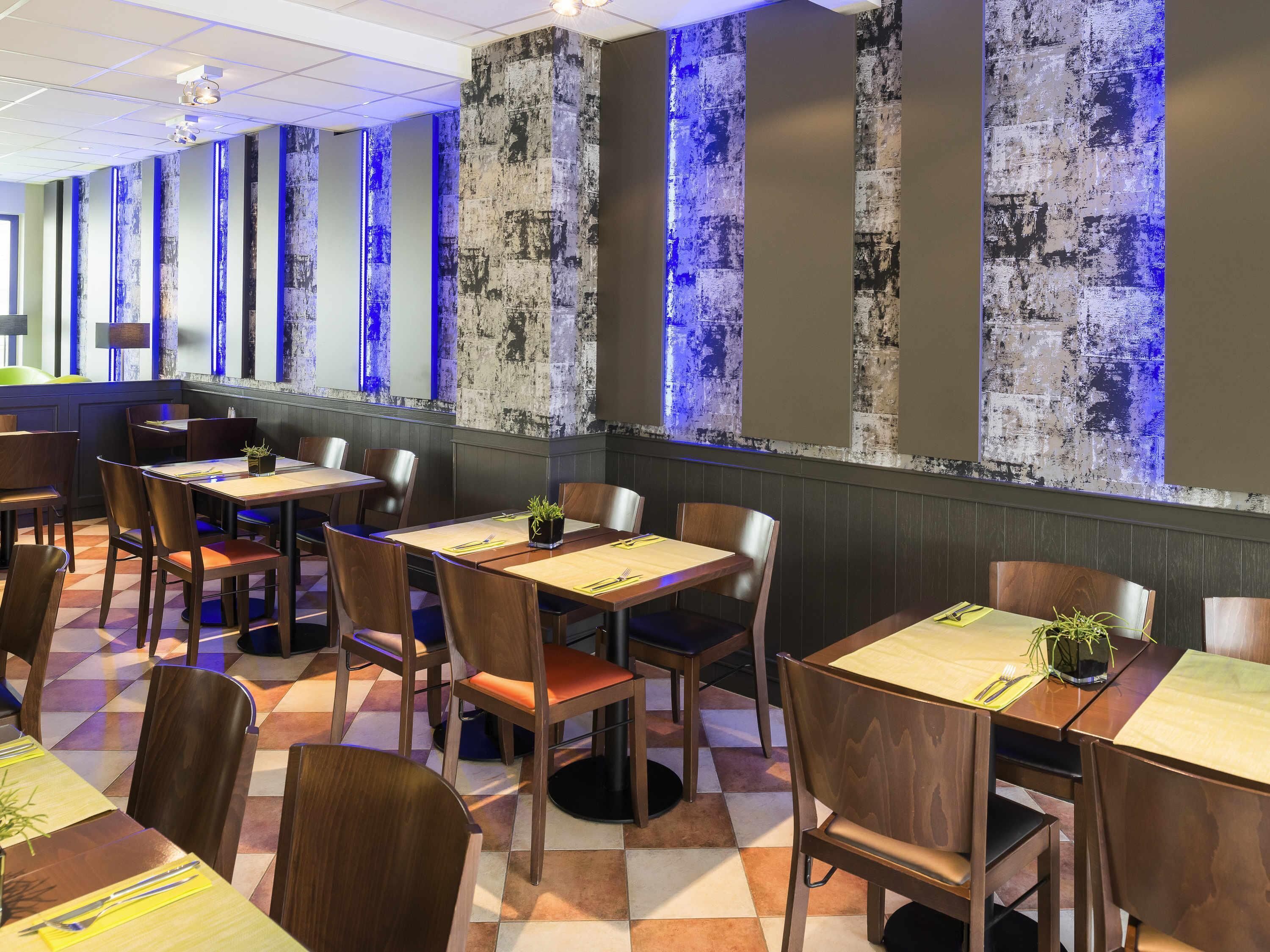 A restaurant interior with wooden tables and chairs, a checkered floor, and a wall with vertical textured panels.