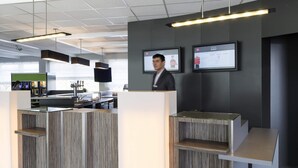 Una recepción con diseño moderno, un televisor de pantalla plana y una pantalla digital que muestra tarifas de habitaciones.