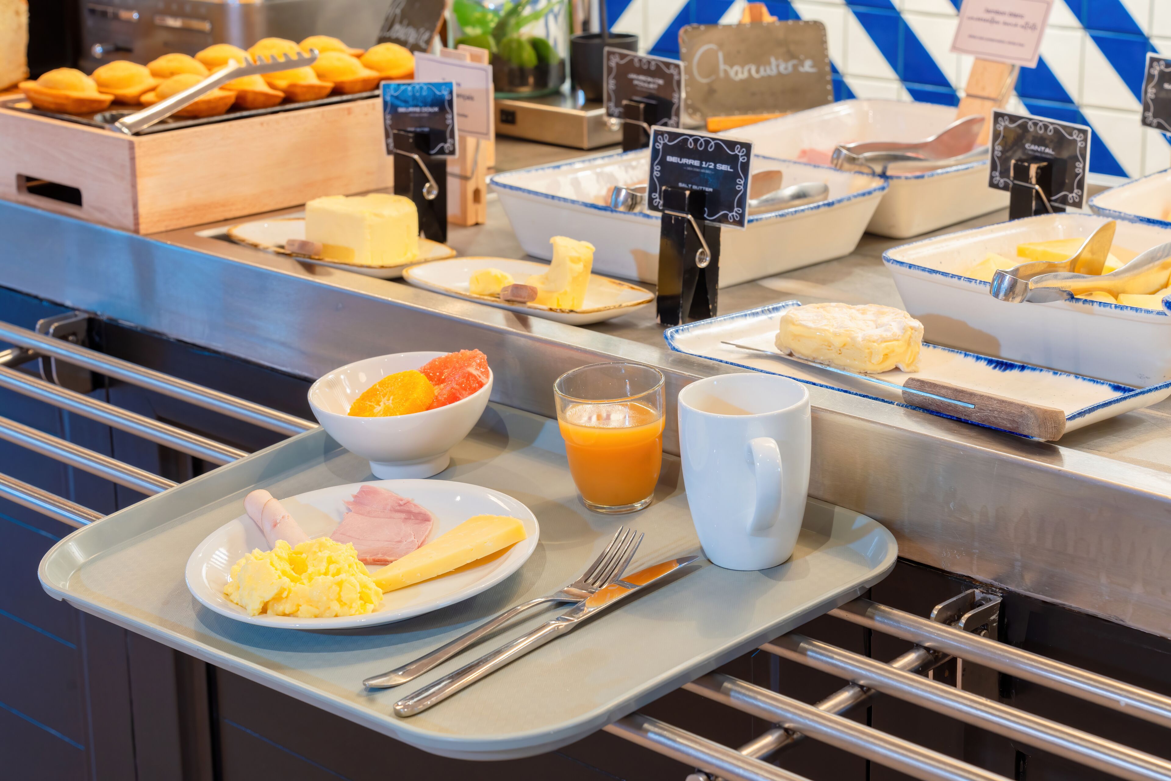 Un bufé de desayuno con diversos alimentos y una bandeja de cubiertos.