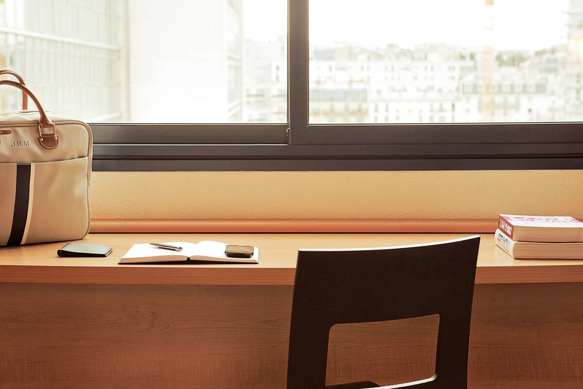 Un bureau avec une chaise, un sac à main, un portefeuille, un stylo, un téléphone intelligent et des livres.