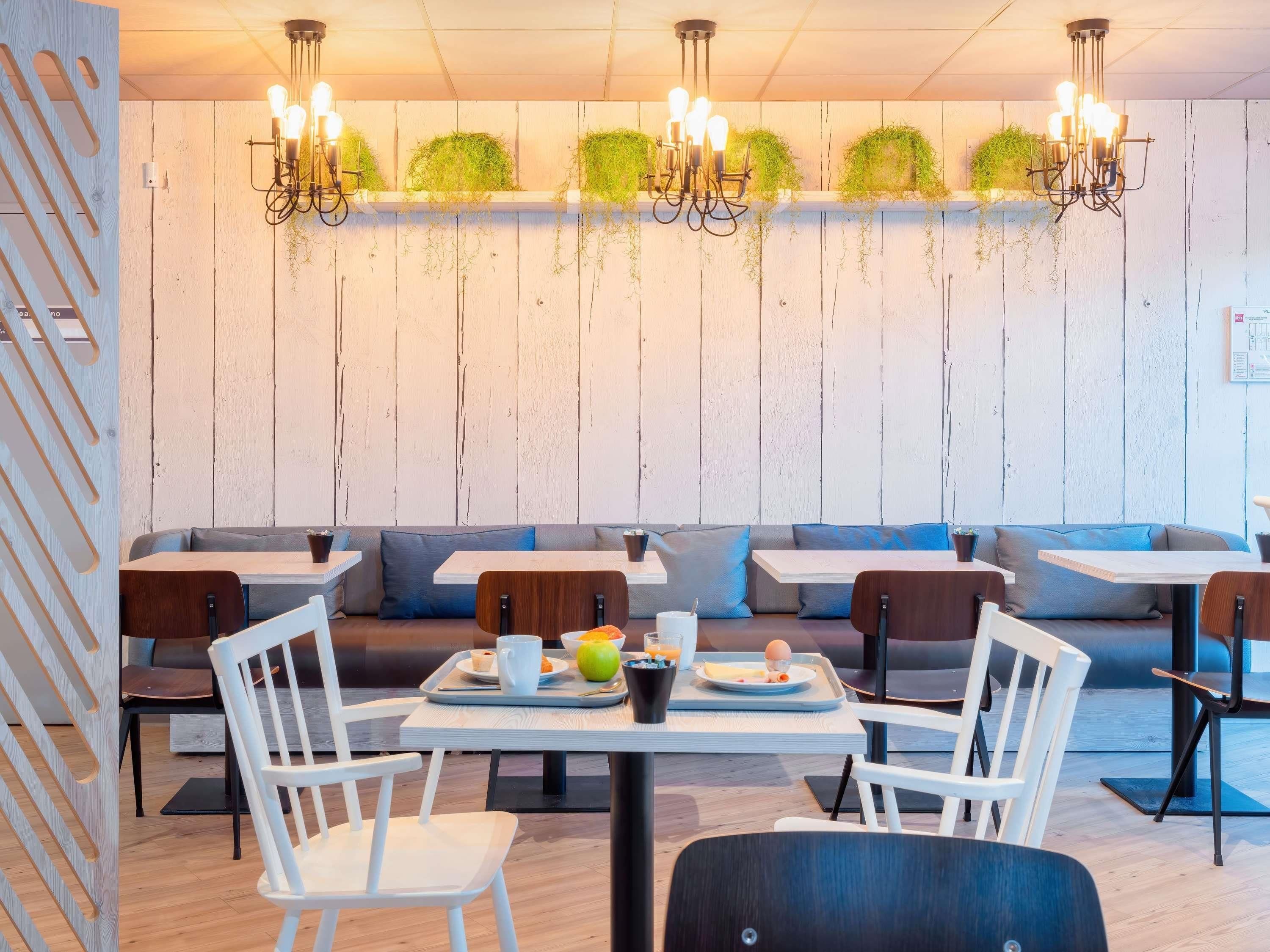 Een moderne eetruimte met houten wanden, witte meubels en groene planten.