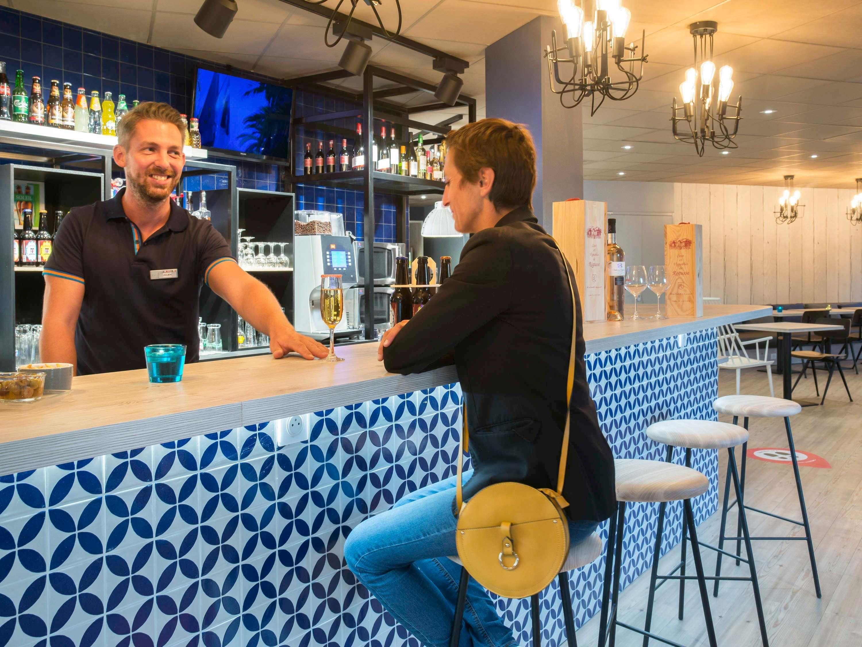 A bar area with a counter, stools, and a television screen in the background.