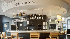 A bar area with a curved ceiling, wooden bar stools, and a variety of bottles and glasses on shelves.