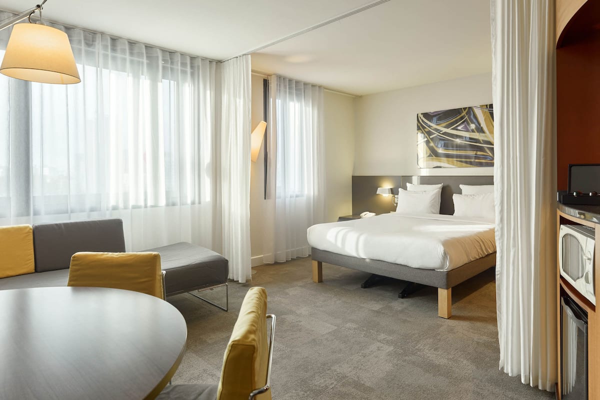 Een hotelkamer met een bed, een slaapbank, een eettafel en een televisie.