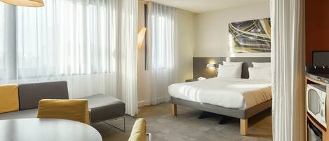 Une chambre d’hôtel avec un lit, un canapé, une table à manger et un téléviseur.