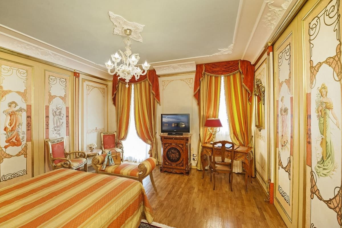 Une chambre d’hôtel dotée d’un grand lit, d’un bureau, d’une télévision et de décorations murales élaborées.