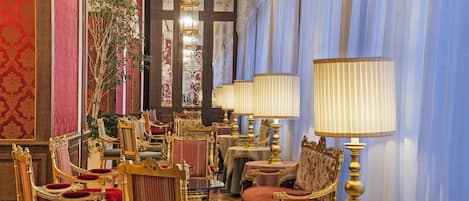 A luxurious room with ornate furniture, including gold-accented chairs and tables, and a large mirror.